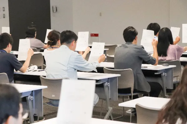 写真：研修参加者がプリントを目の前に掲げているところ