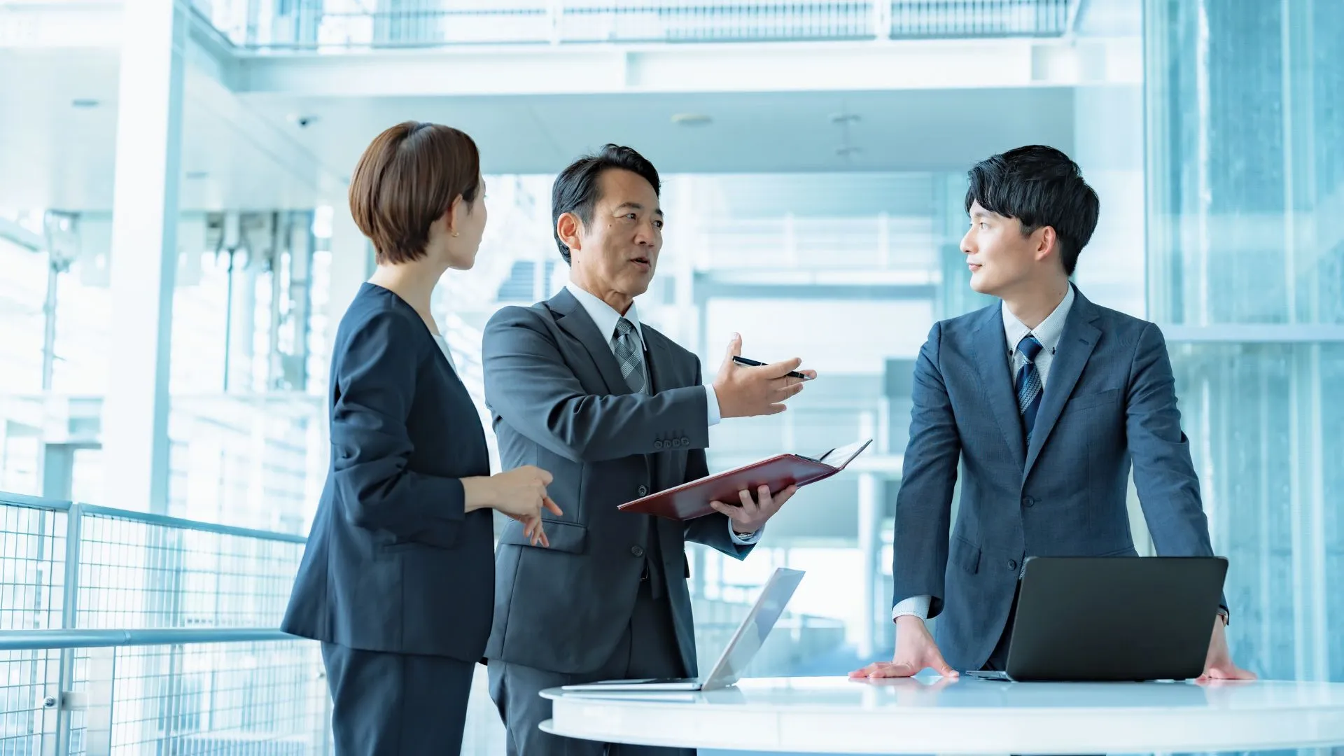 オープンスペースで資料を示しながら、関係者と方針をすり合わせている場面