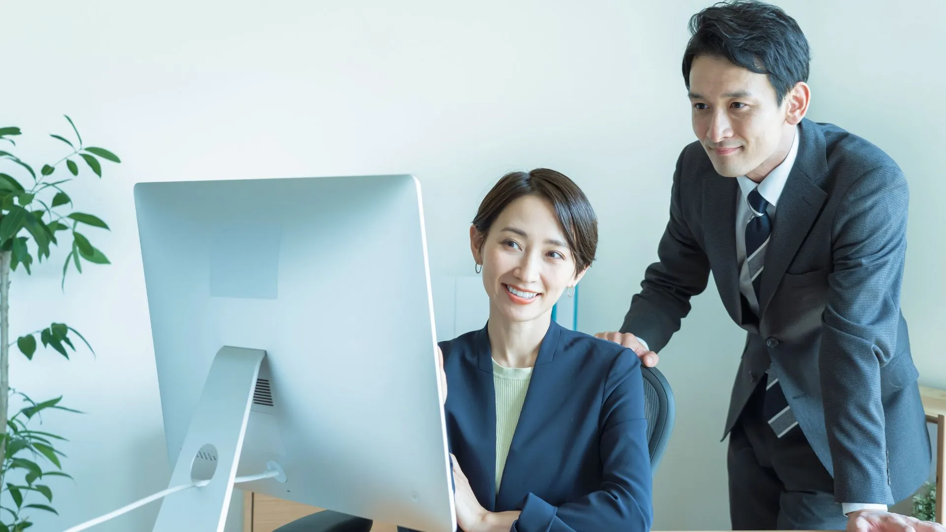 デスクで画面を見ながら、上司と担当者が作業内容を確認している様子