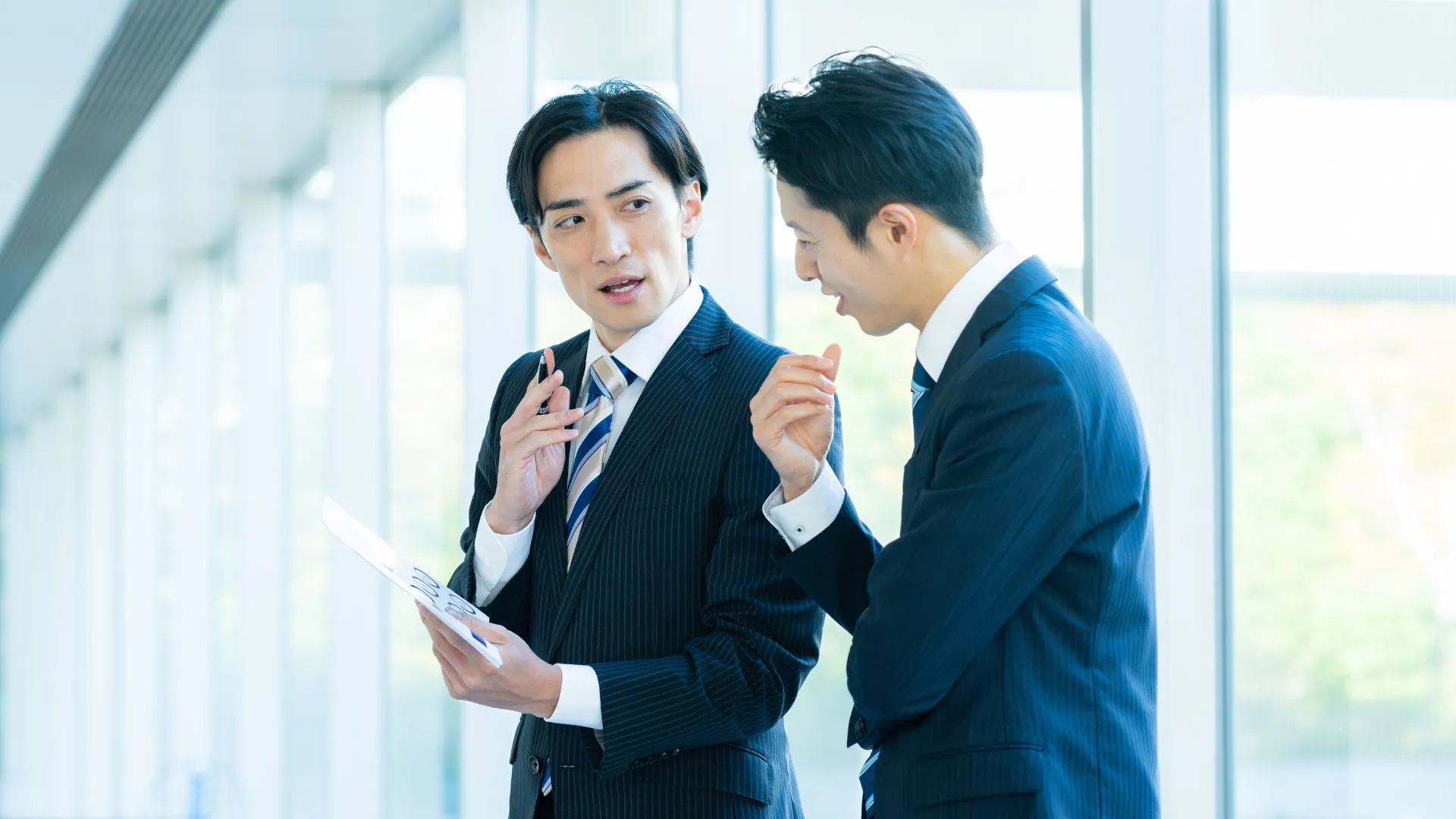書類を見ながら話をする二人のビジネスパーソン