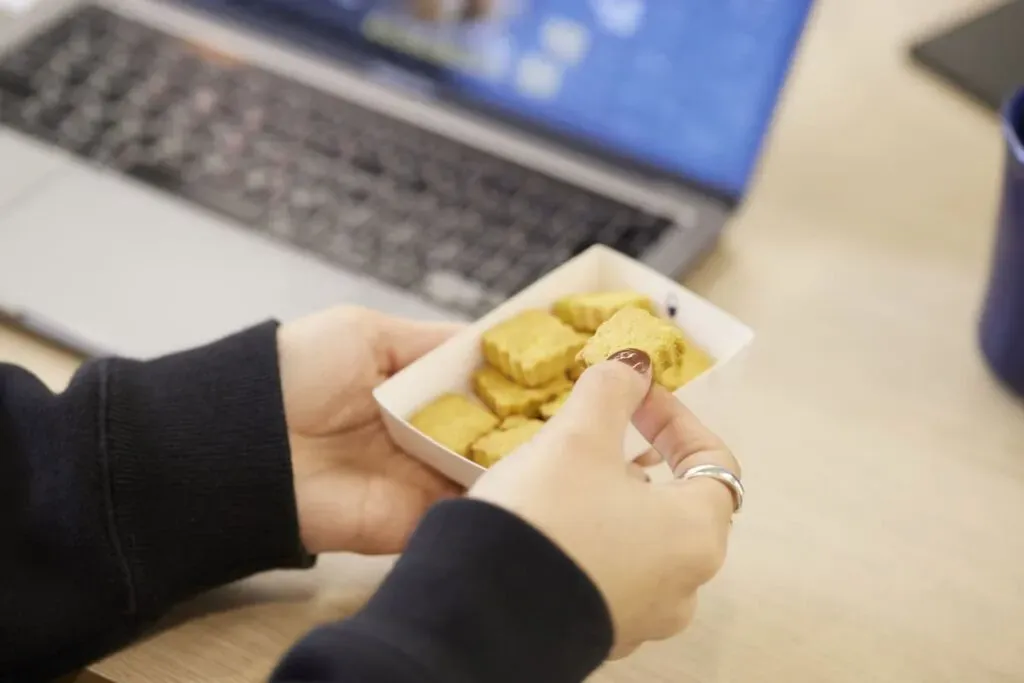 ノートパソコンで仕事をするかたわら、スナックミーの置き菓子をつまむ様子