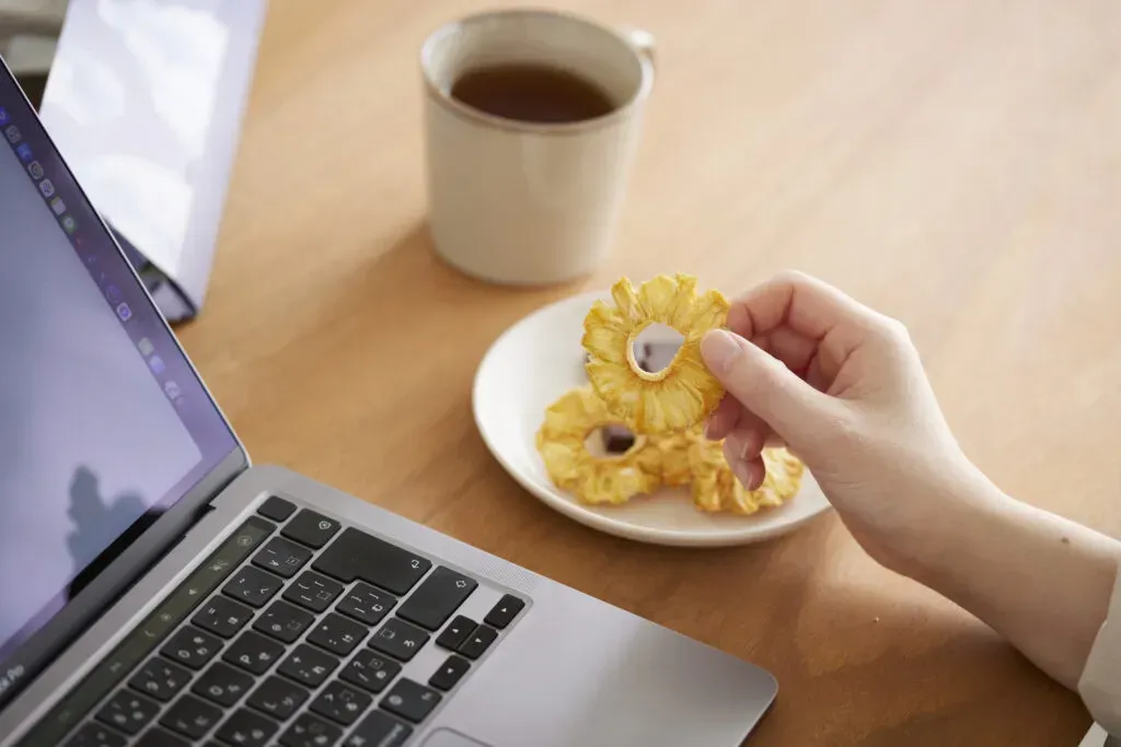 ノートパソコンで仕事をしながらスナックミーオフィスのドライフルーツを食べる様子