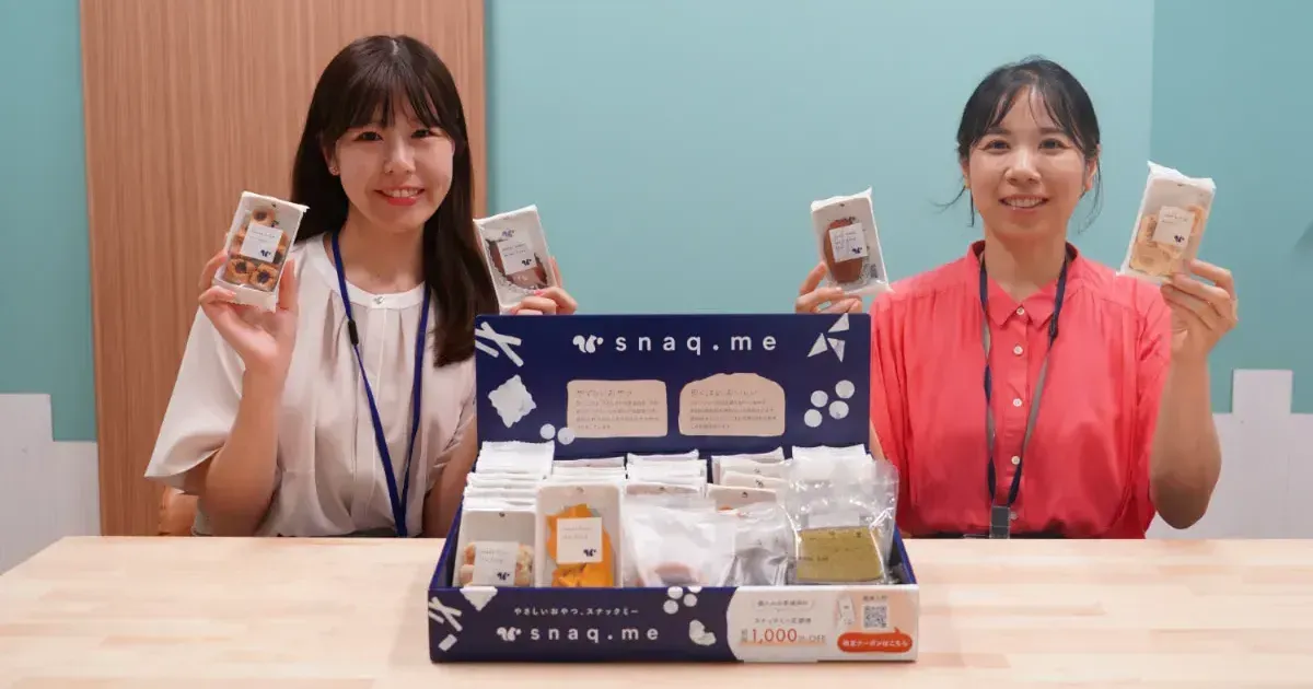 スナックミーオフィス導入企業『株式会社ロビンソン』さまのスタッフが、スナックミーの置き菓子を手に持った写真
