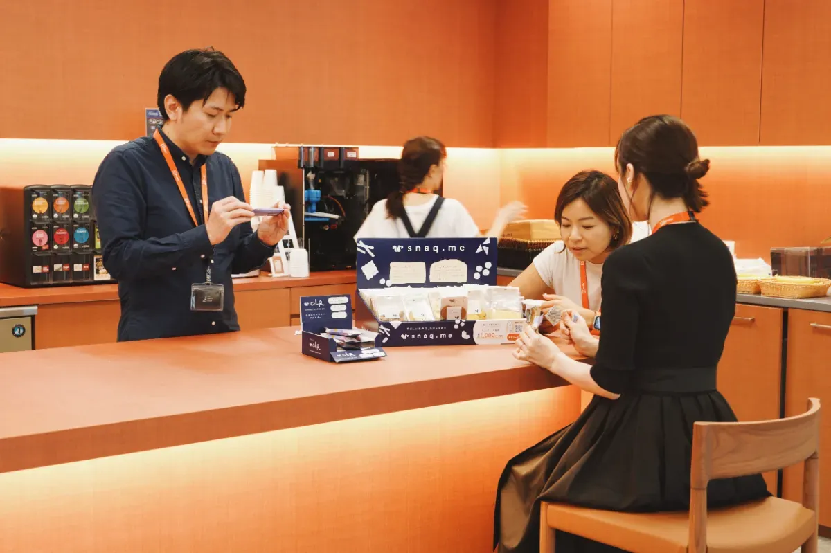 スナックミーオフィス導入企業『UiPath株式会社』さまのスタッフが、カフェスペースで置き菓子を囲む様子
