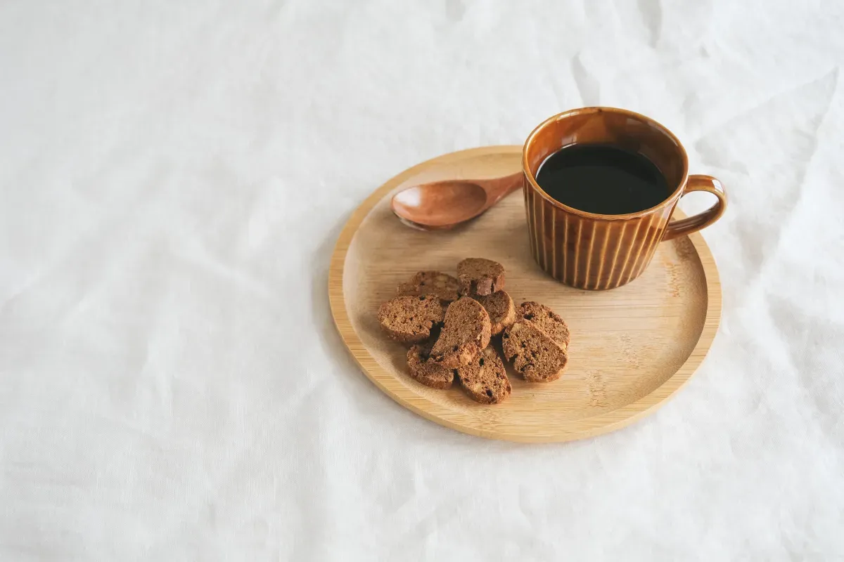 スナックミーのデカフェコーヒーのカップとビスコッティが盛られた木製トレイ