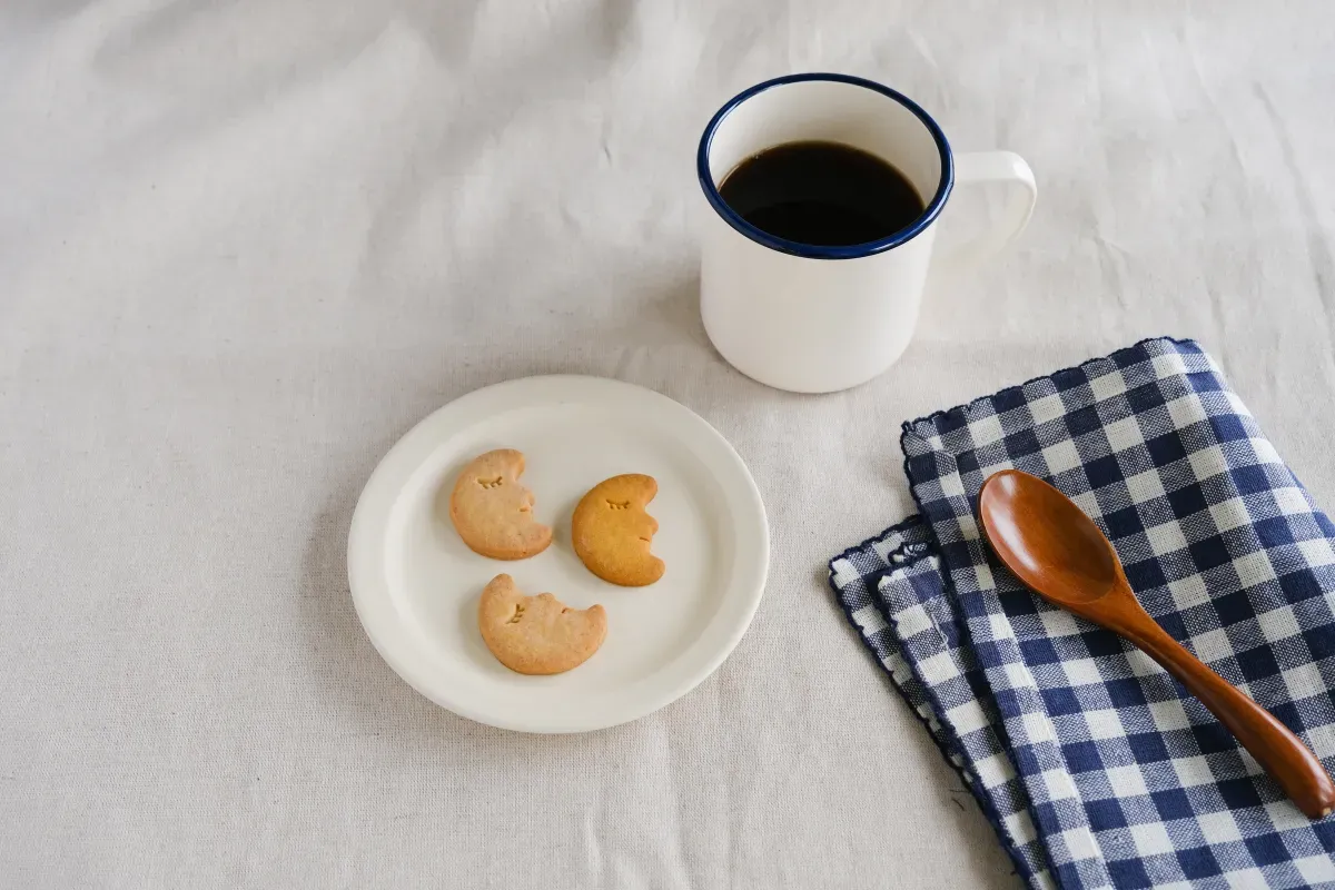 スナックミーの三日月型クッキーが盛られたお皿、コーヒーカップなどが並ぶテーブル