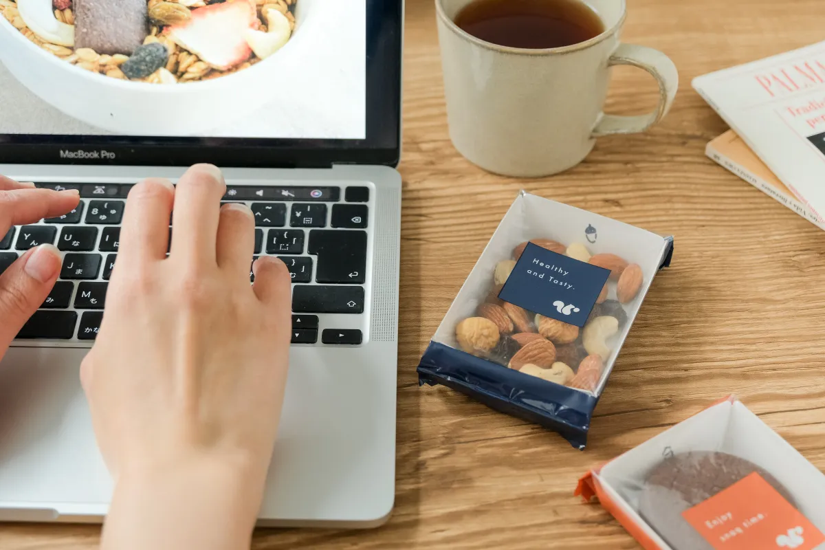 タイピングをする傍らにあるコーヒー、ナッツ