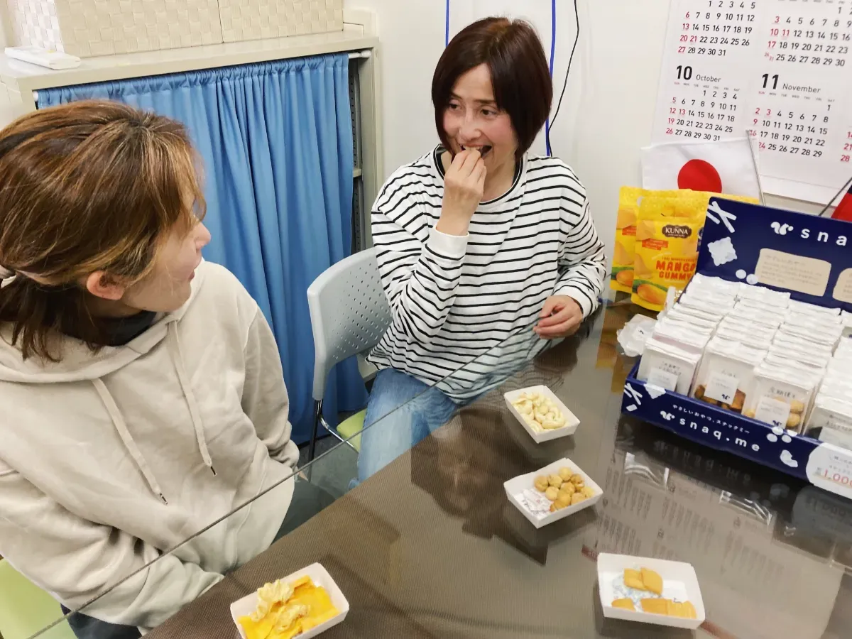 スナックミーオフィスの置き菓子を囲む『株式会社ジャパン・ファームプロダクツ』の社員