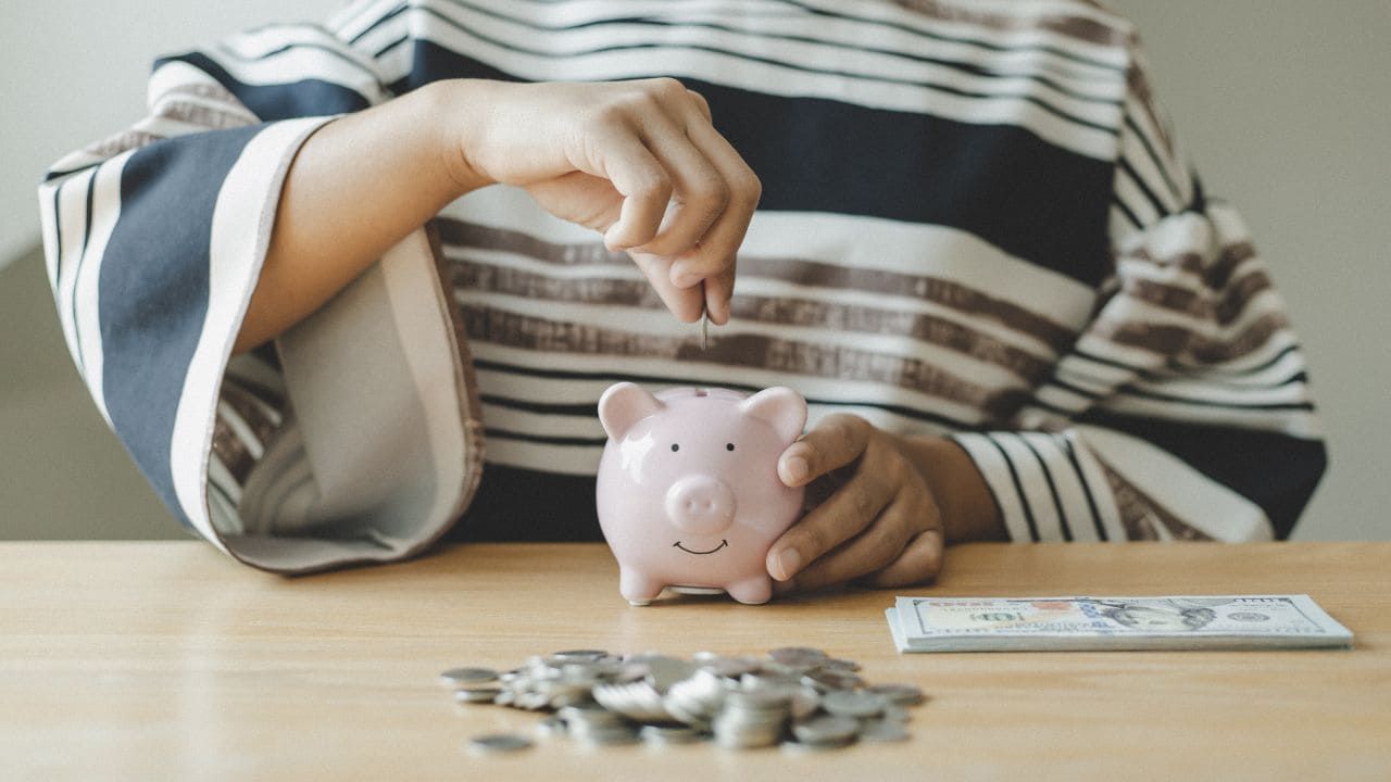 豚の貯金箱に貯金をしている人