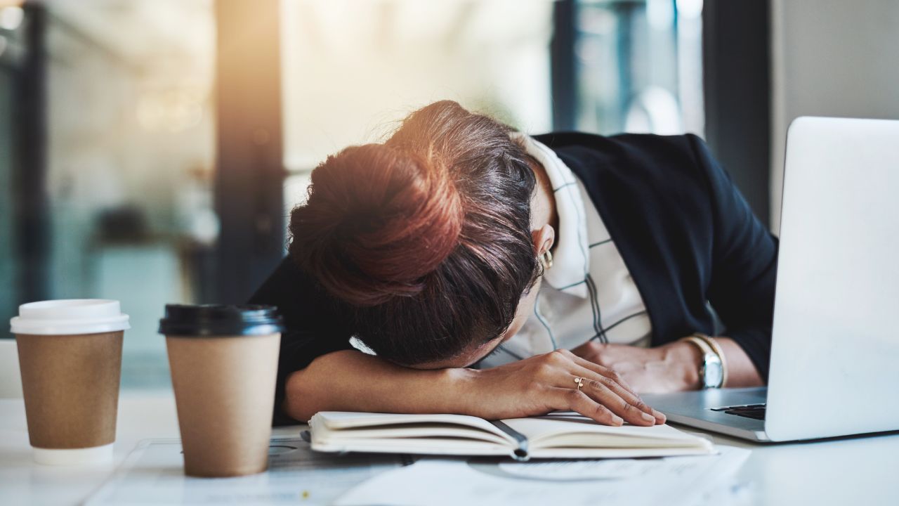 机の上で項垂れる女性の画像