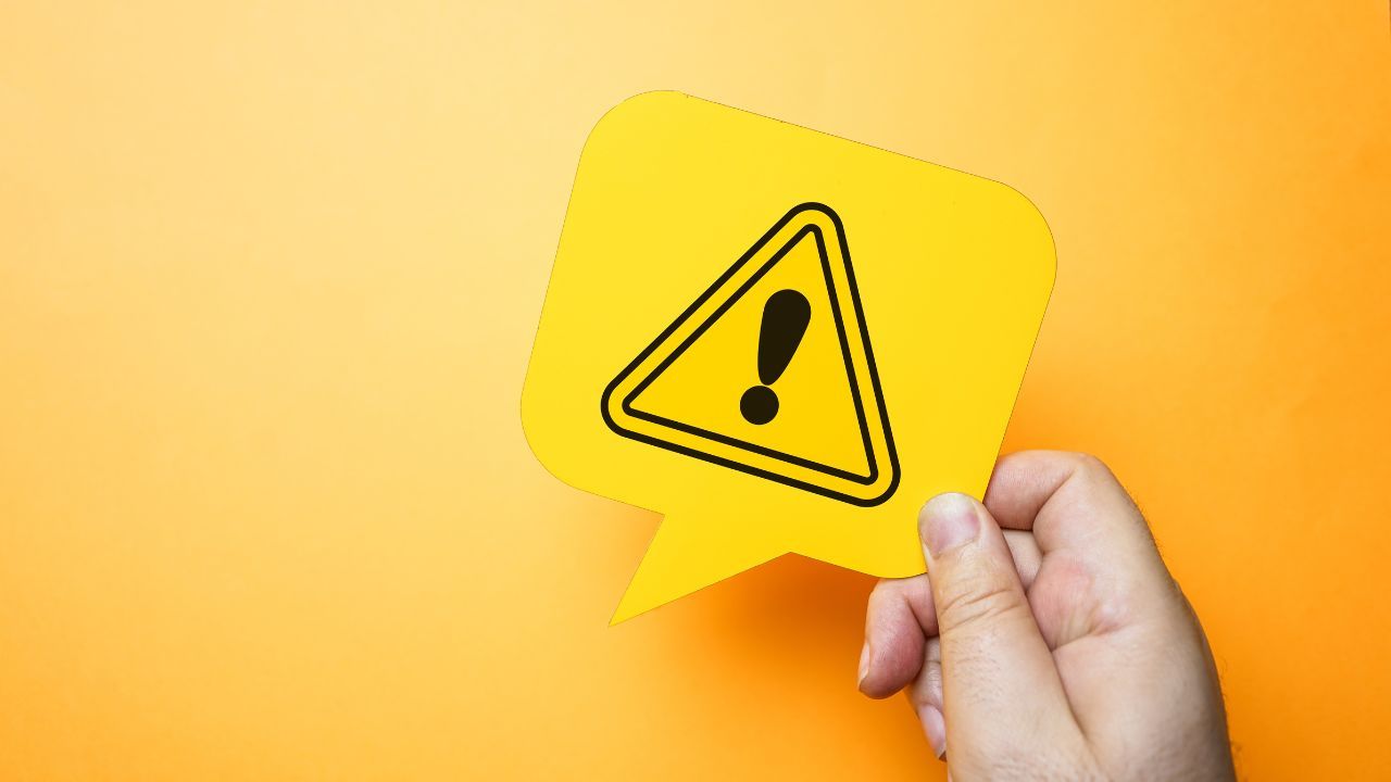 注意マークのステッカーを持った人の画像