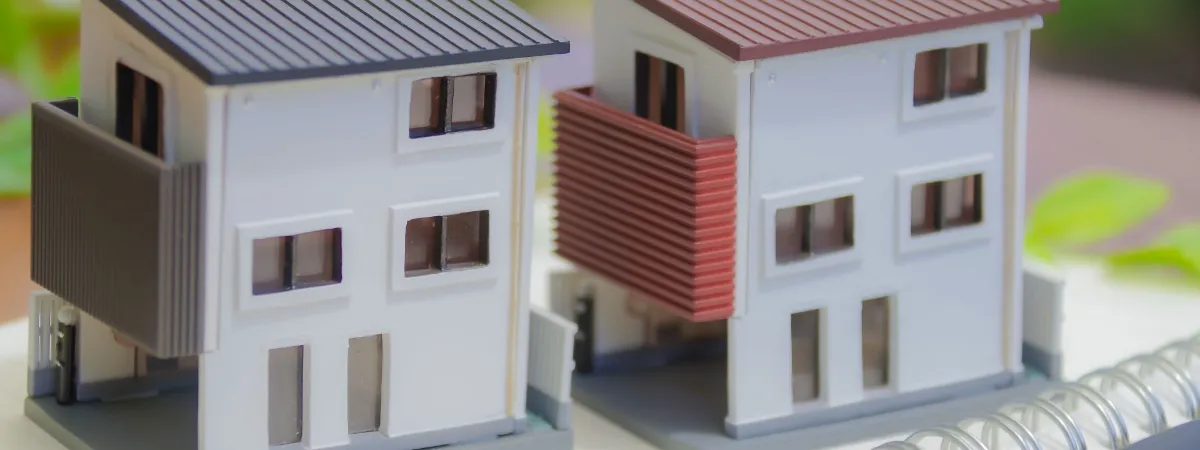 小さな白い二階建ての住宅模型と住宅図面