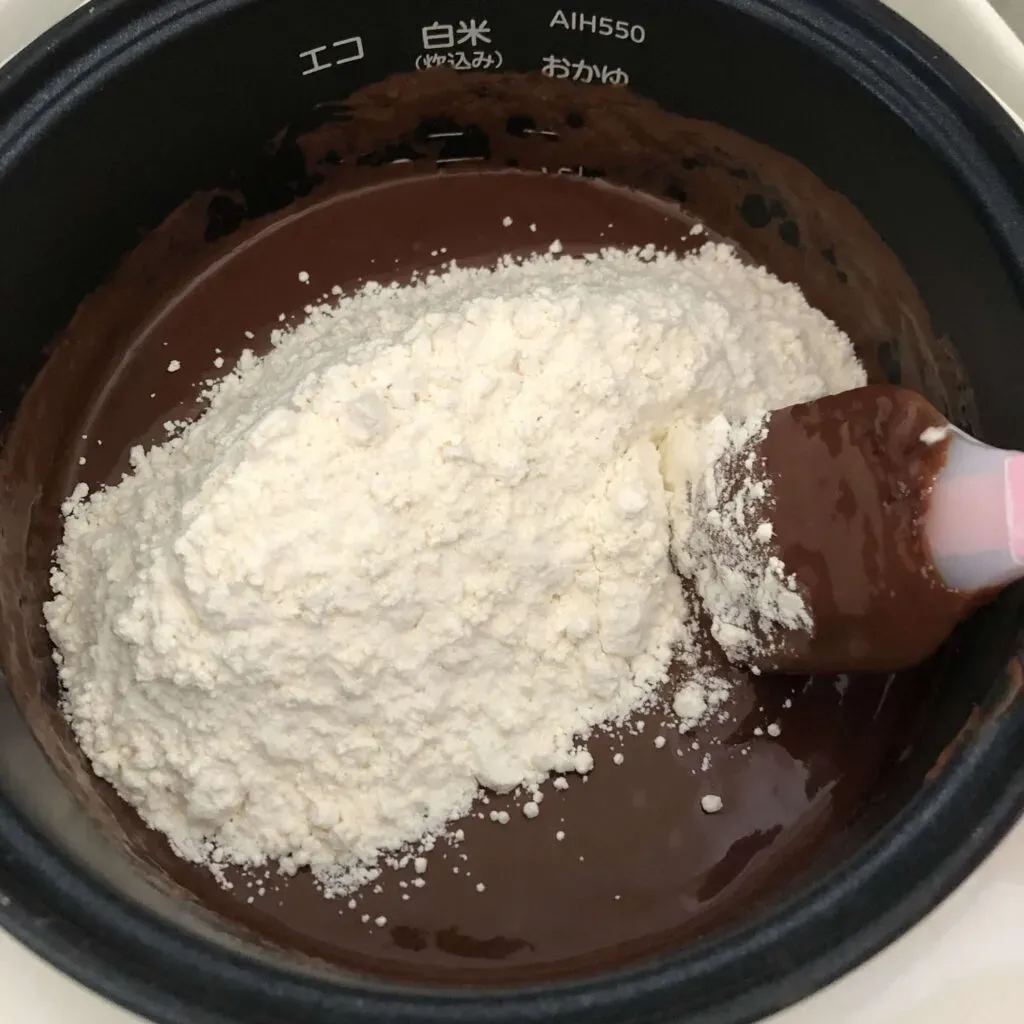 炊飯器の釜でチョコレートケーキの生地を混ぜる様子