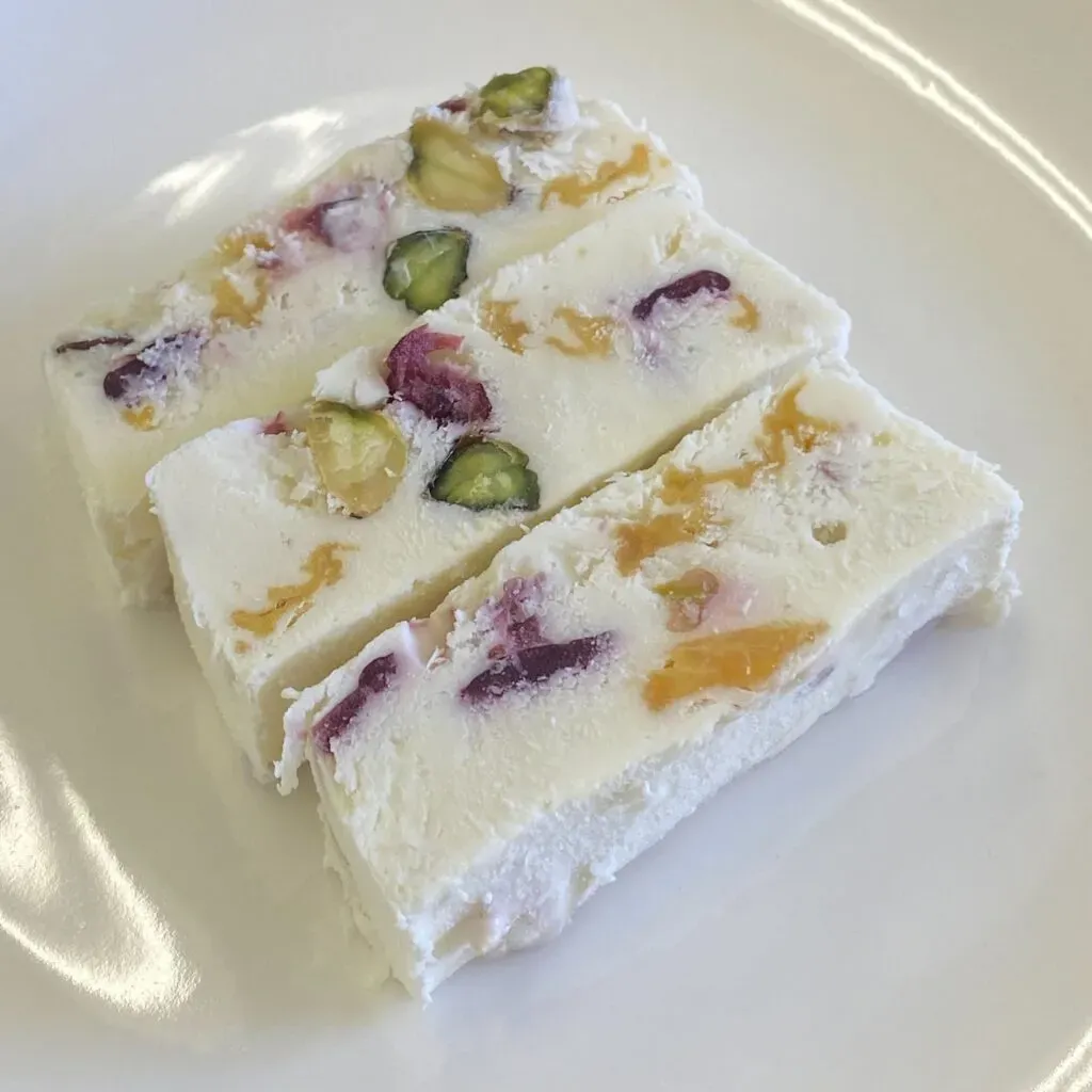 スナックミーの『贅沢チーズアイスケーキ パインとピスタチオ』。断面に色とりどりのフルーツが見えています。