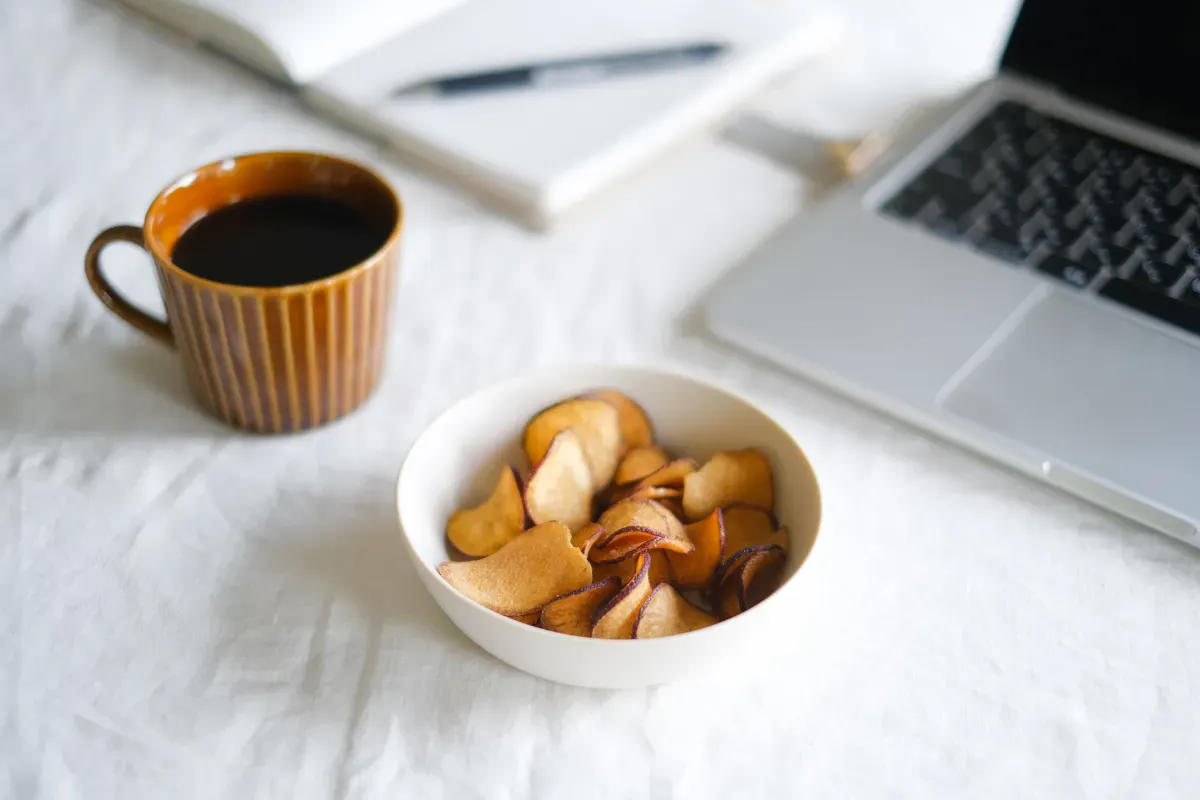 パソコンのそばにコーヒーとお菓子が置かれた様子