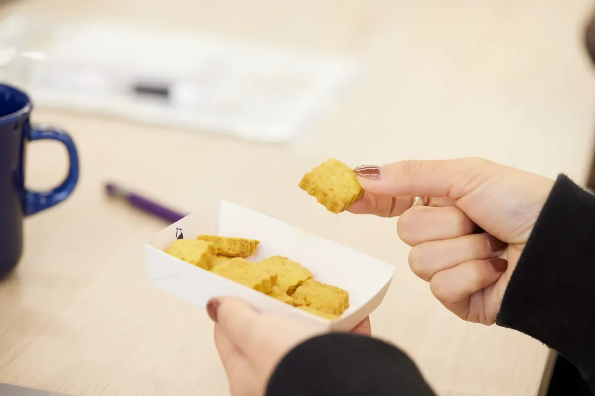 デスクで仕事中にスナックミーオフィスの置き菓子をつまむ女性従業員