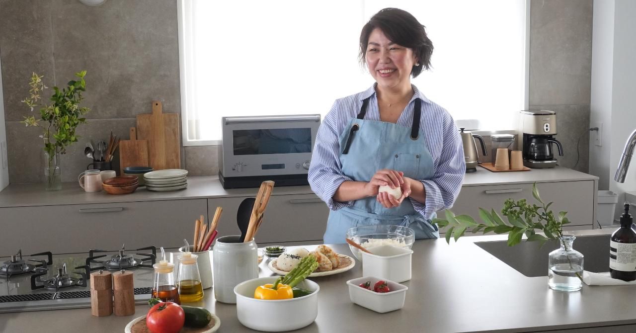 キッチンカウンターに食材を並べて笑顔の女性
