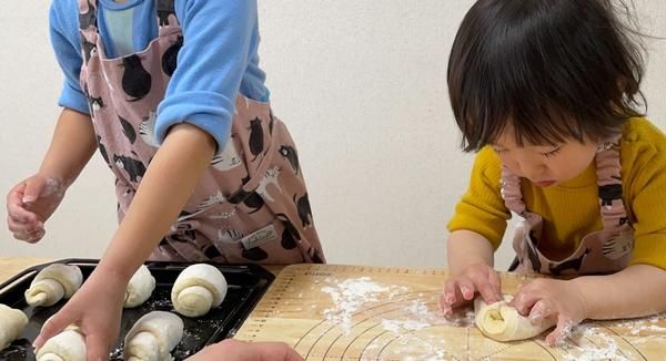 こね台の上でパン生地をこねている子ども