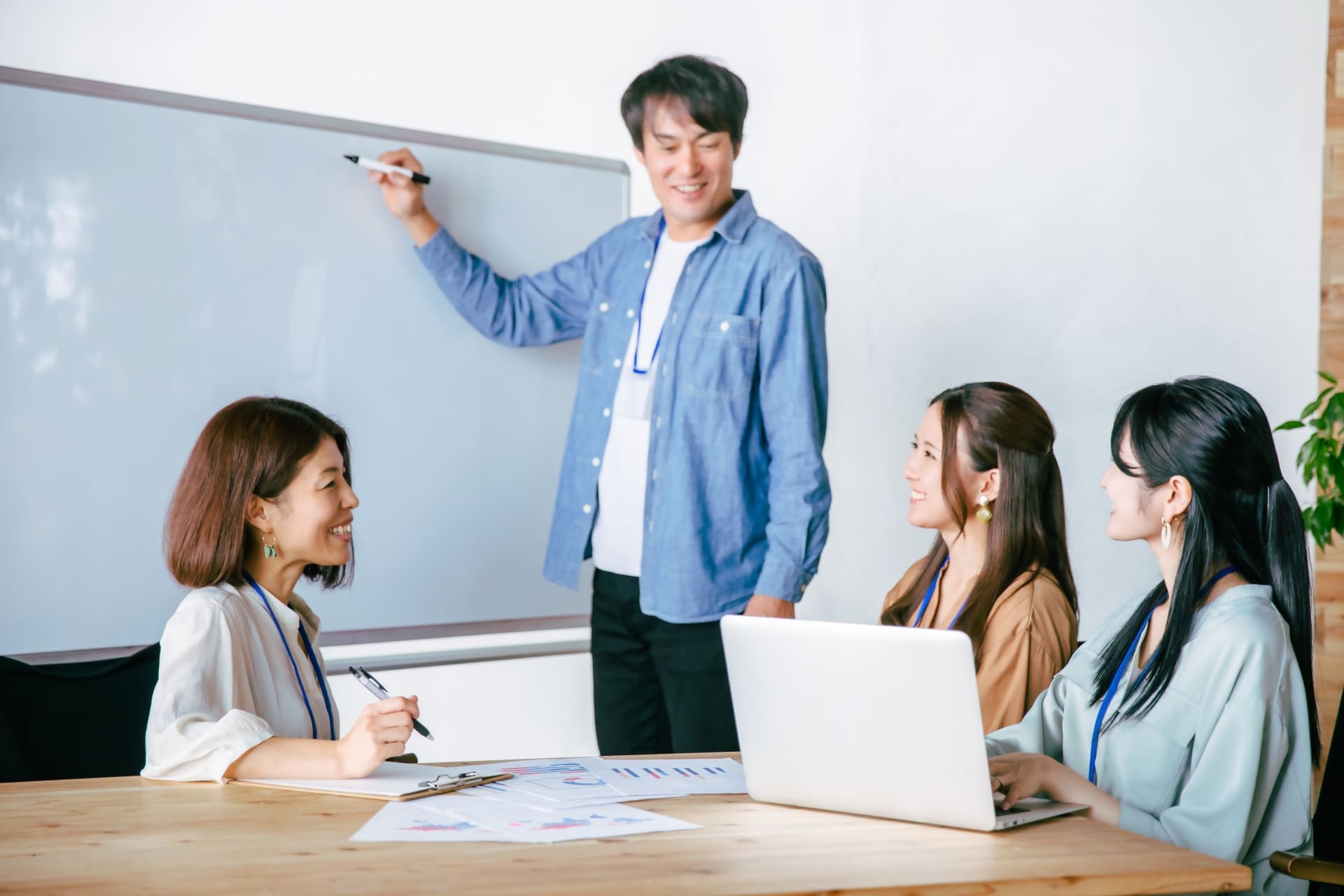 ホワイトボードを前に会話する男女のビジネスマンの画像