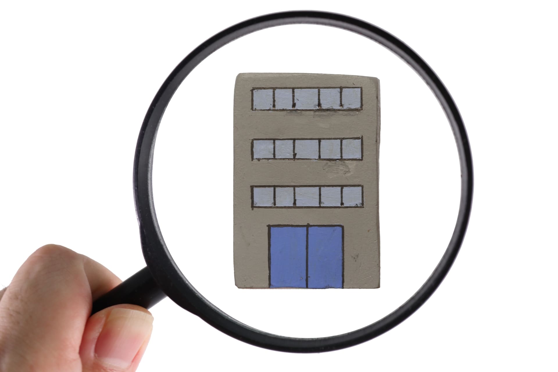 虫眼鏡の向こうに会社のビルが移っている画像