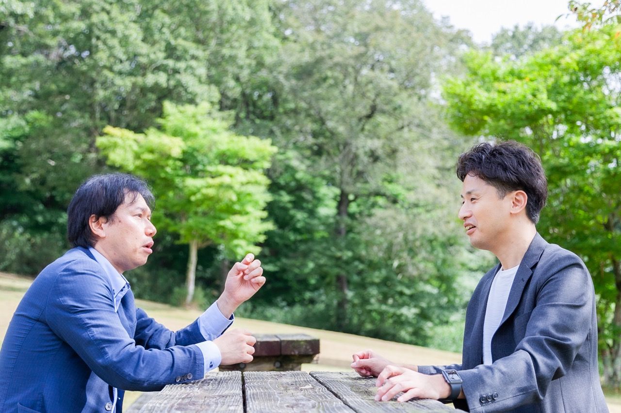 屋外で向き合いながら座り話し合う内垣戸先生と前田先生の写真