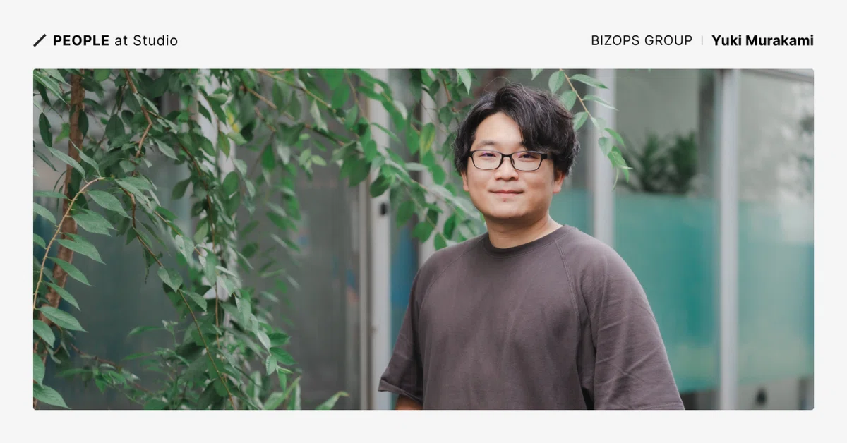カバー画像、People at Studioのテキストと、立ち姿で写真に収まるMurakamiさん。