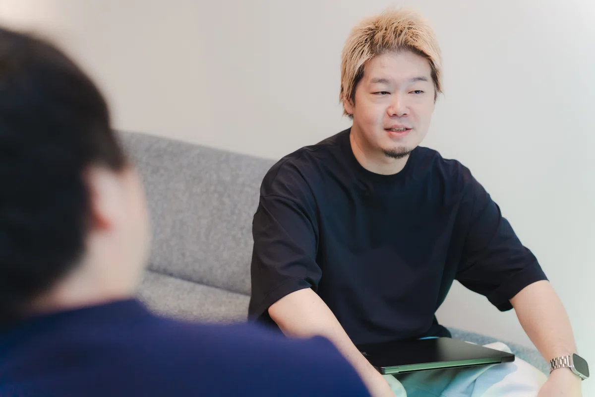 写真。ソファーに腰掛け、インタビューに応じるYagiさん。目線をインタビュイーがいない方に向け、言葉を紡ぎながら話している。