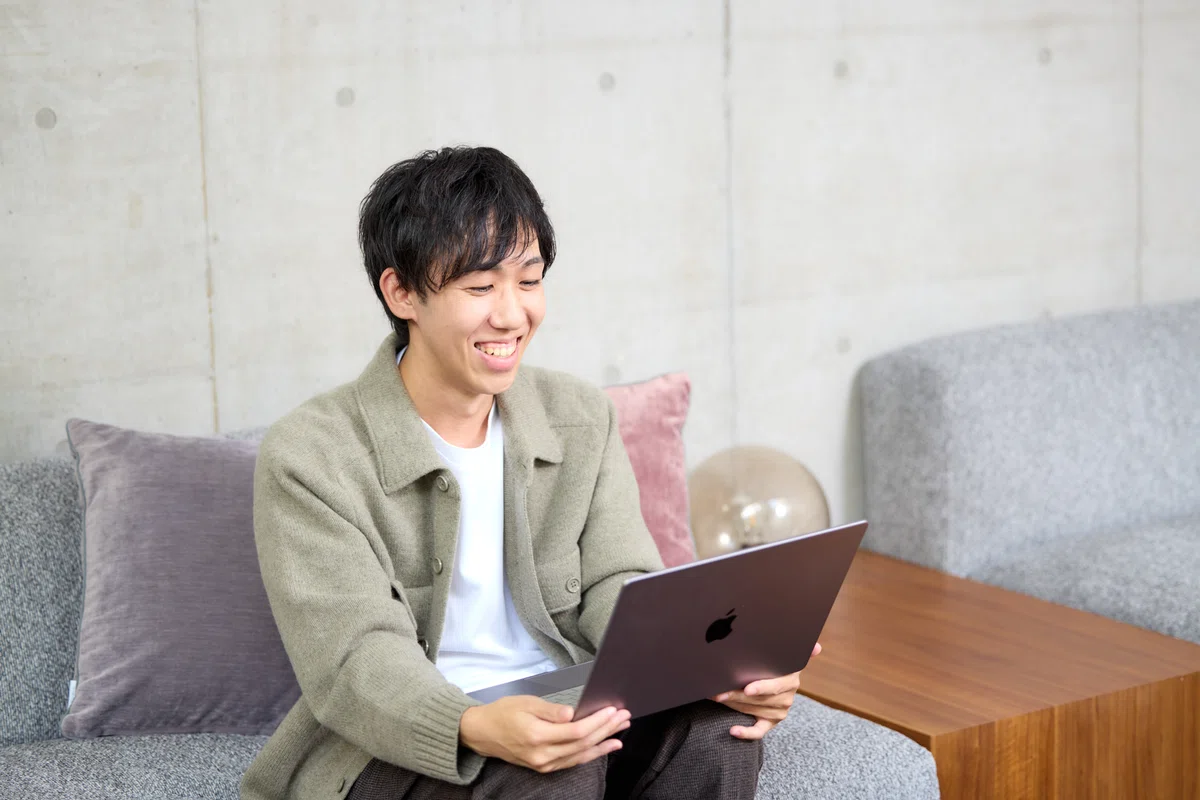 写真。手元に抱えたPCに目線を落としている様子。