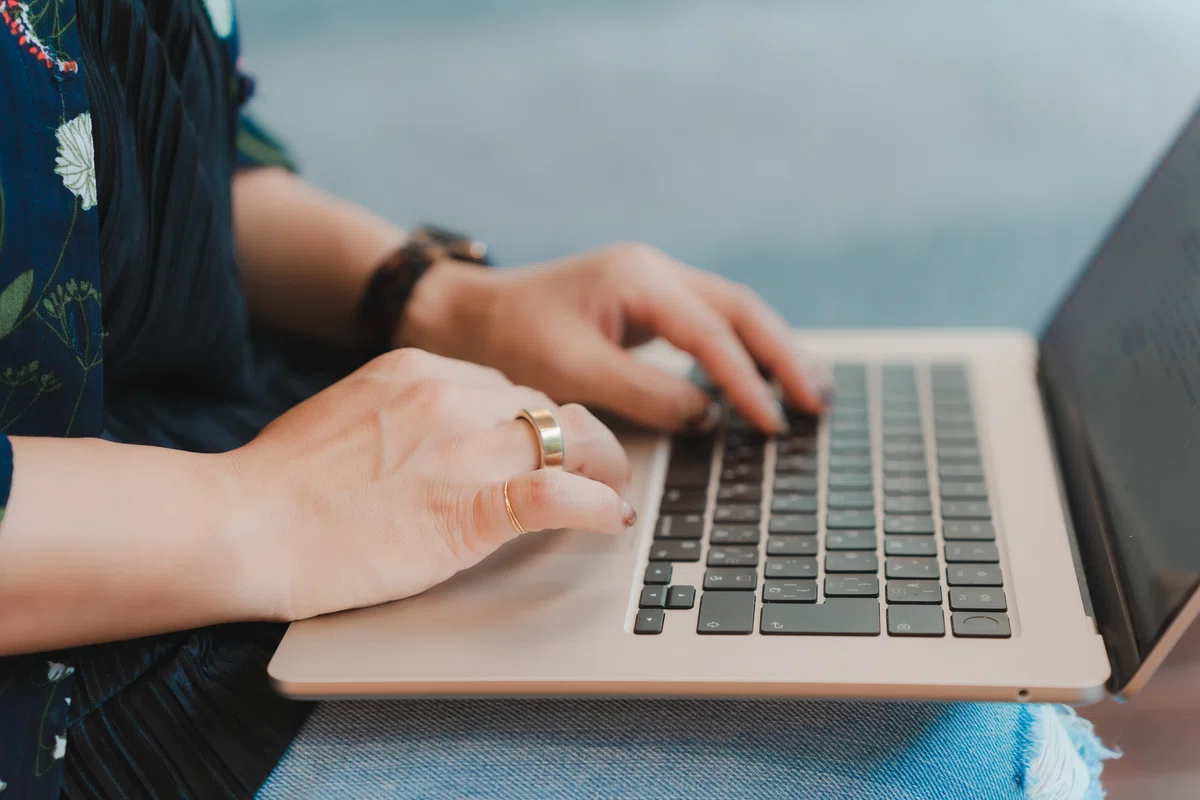 写真。PCのアップ。Caoryさんがキーボードを操作する様子を、右側から切り取っている。