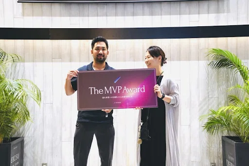 写真。2024年上半期社員総会にて、MVPを受賞した際の様子。CEO石井と並び、「The MVP Award」と記されたボードを胸元に掲げている。