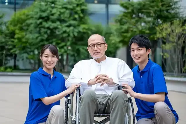 車いすのシニア男性と介護施設スタッフ