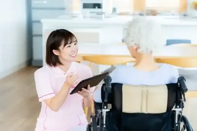 車椅子に乗った女性をサポートする介護士