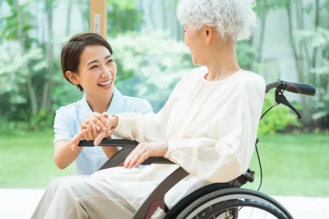 介護士が車椅子に乗る高齢者に話しかける様子