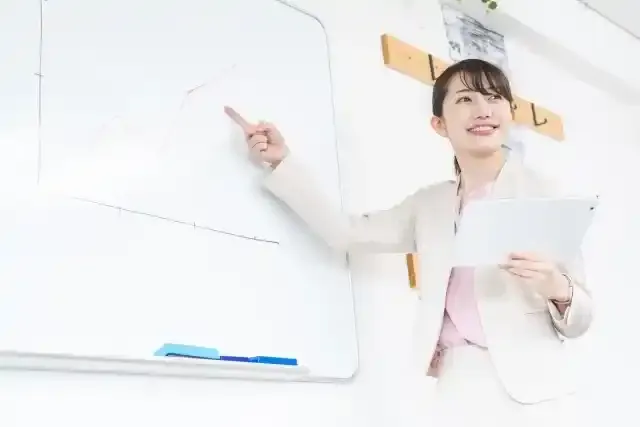 ホワイトボードを指さす女性