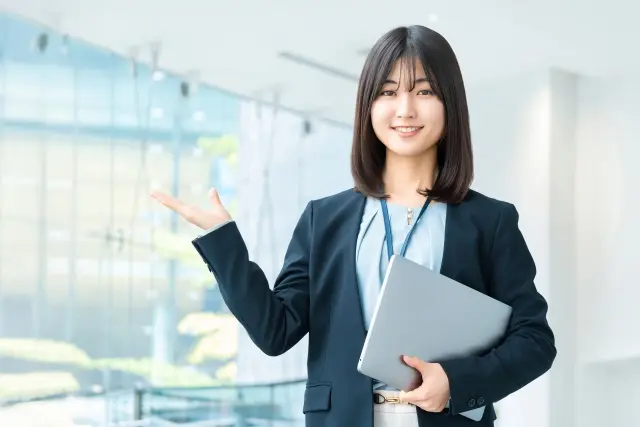 パソコンを持って案内をする笑顔の女性
