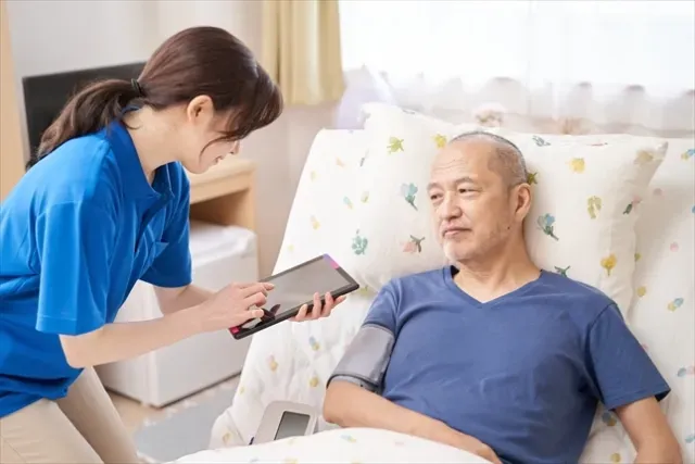 高齢者の血圧をタブレットで記録入力する介護士