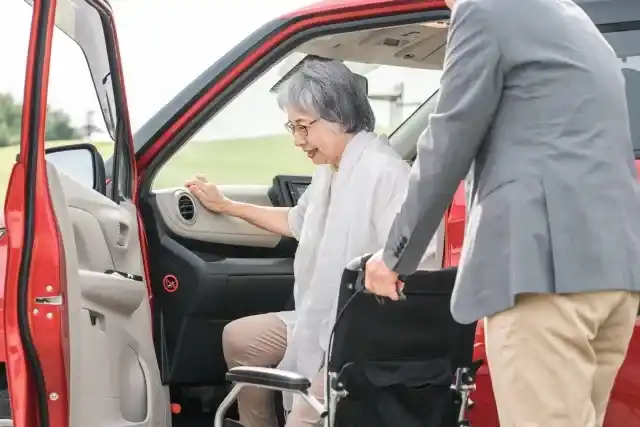 車を降りて車椅子に移乗する高齢女性