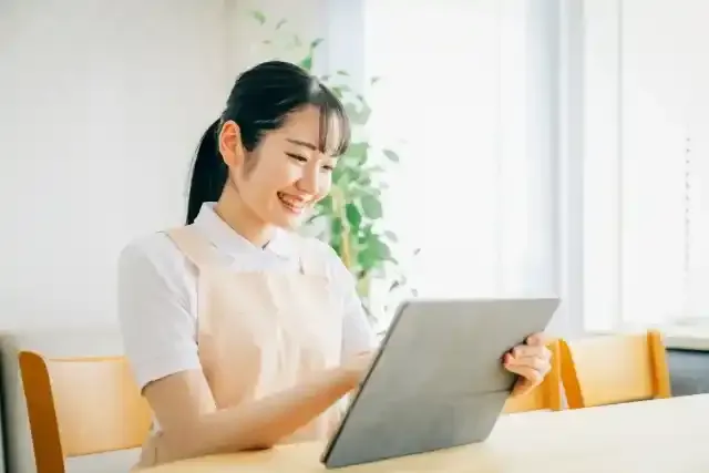 タブレットPCを使うエプロン姿の女性