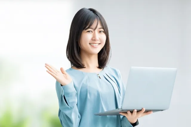パソコンを持って案内をする笑顔の女性
