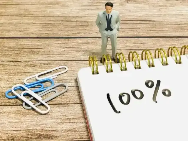 100%と記載されたメモ帳と男性ビジネスマンのイメージ