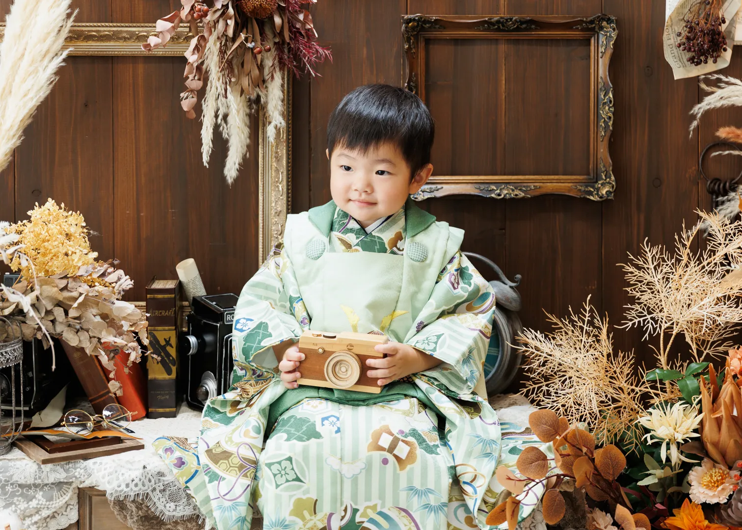 緑の着物を着た男の子が漆器の小箱を持ってアンティーク調の室内に座る七五三記念写真(能美市)|ヤマダフォト