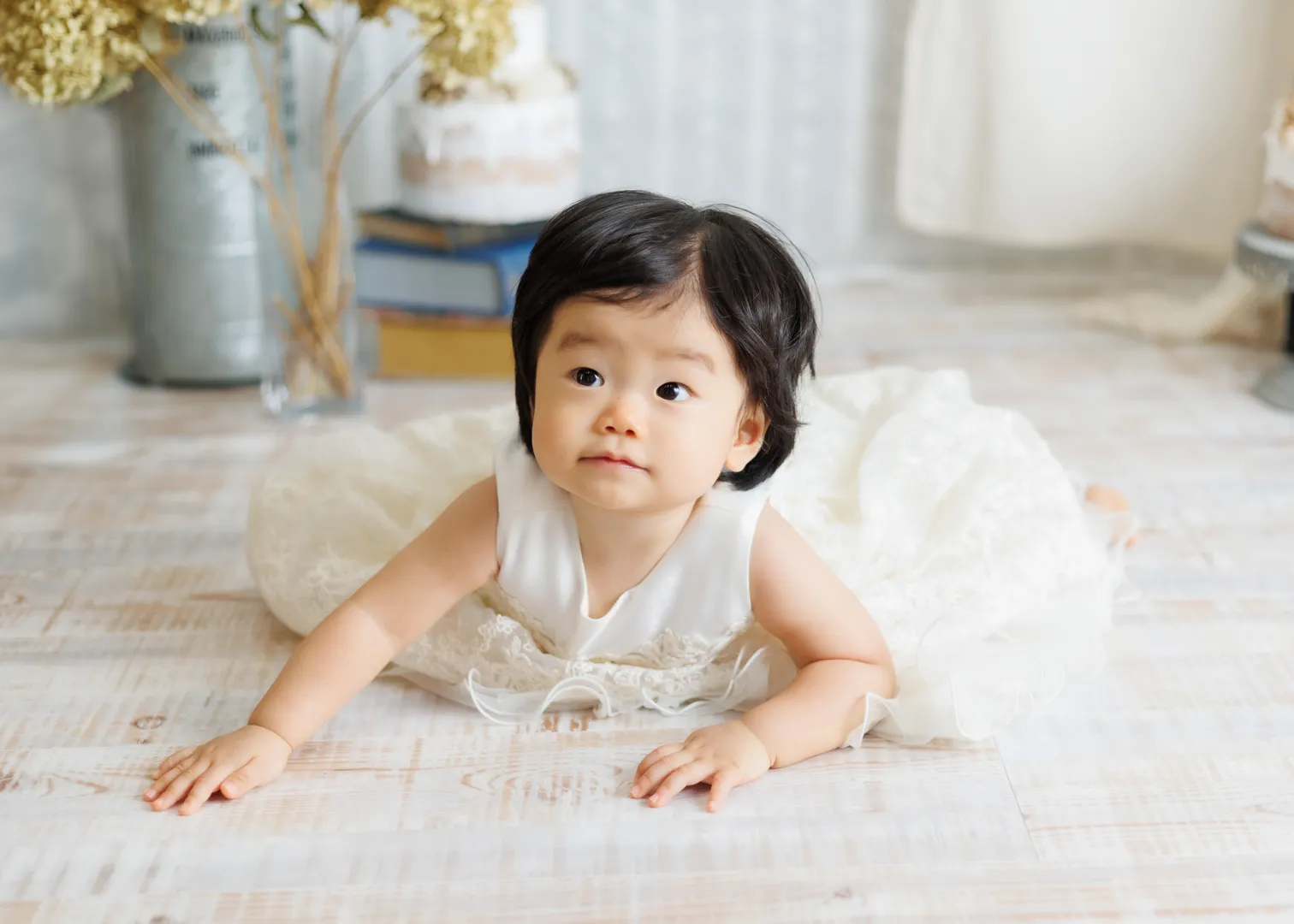白いドレスを着て木の床の上ではいはいする1歳バースデーの女の子（能美市）｜ヤマダフォト