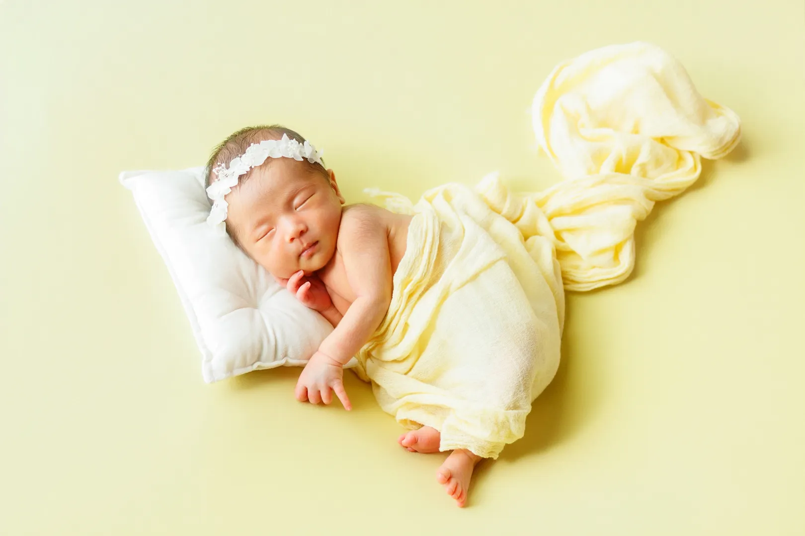 黄色のおくるみに包まれ花冠をつけて眠る新生児の女の子のニューボーンフォト(能美市)|ヤマダフォト