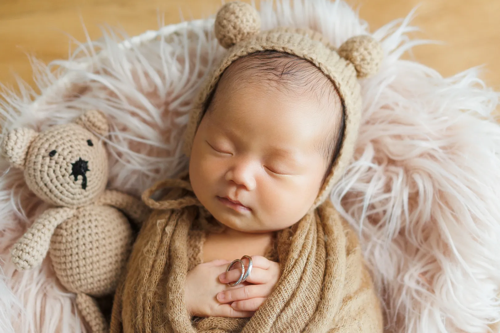 クマのぬいぐるみとファーの布団で眠る熊耳帽子の新生児(川北町)|ヤマダフォト