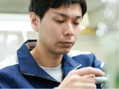 加工部品を手に取り品質を確認するパール技研の技術者