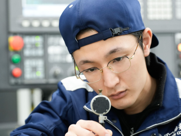 阿部さんが測定器で部品の寸法を確認している様子