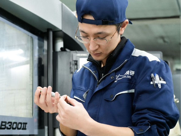 阿部さんが加工した部品を手に取り確認している様子