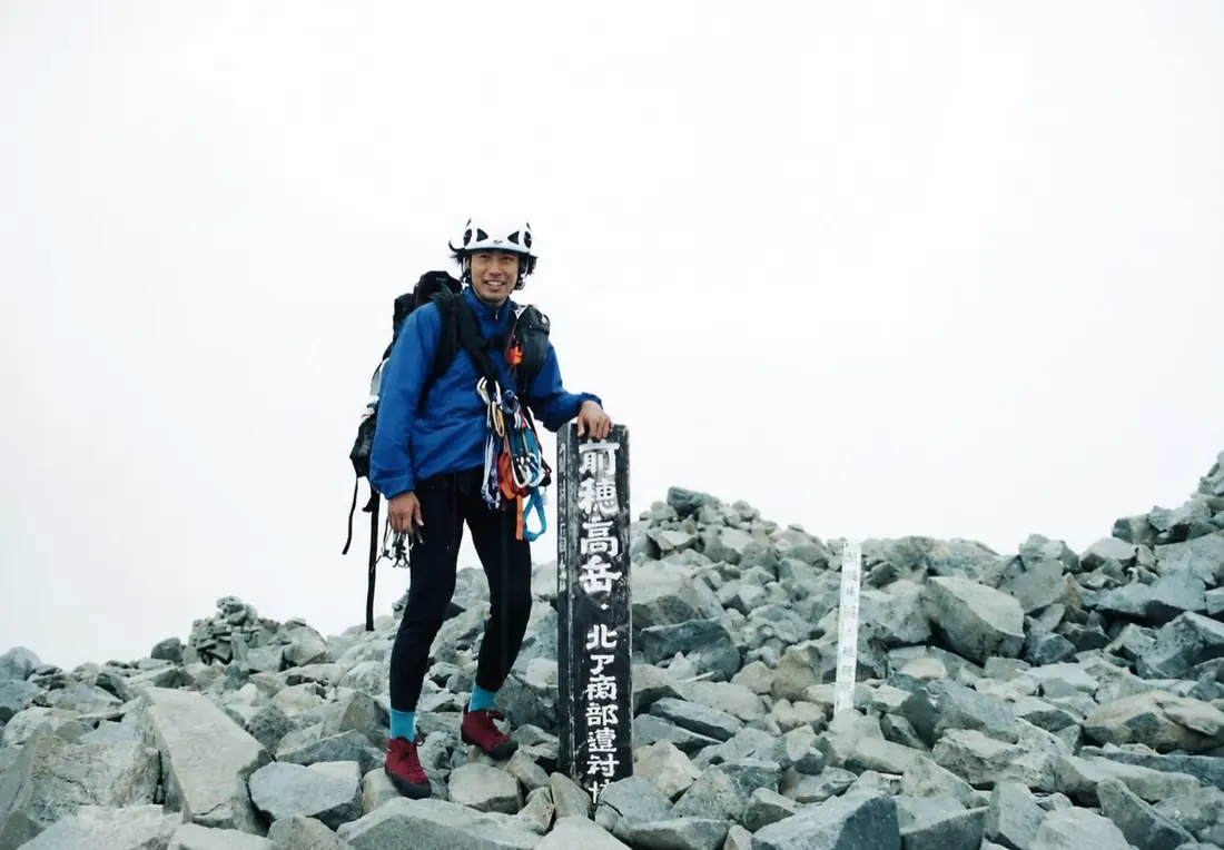 前穂高岳山頂で装備を身につけたカウンセラーの過去写真