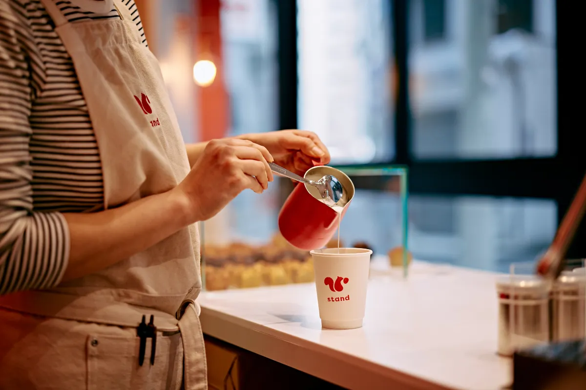 カフェスタッフがカップにドリンクを注いでいる様子
