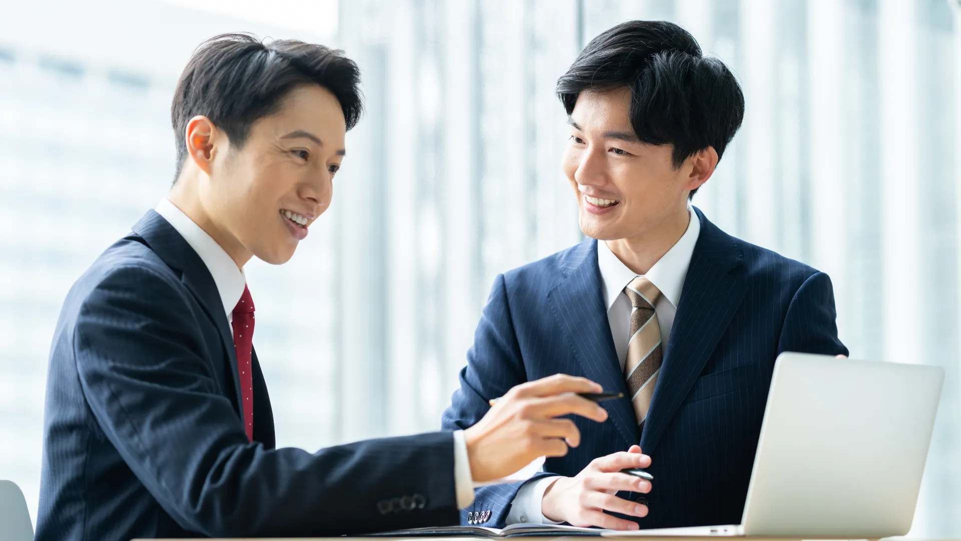二人のビジネスパーソンが書類を一緒に確認している画像。成果物納品のイメージ。